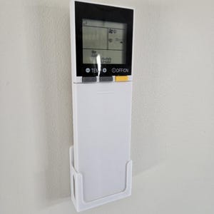 Może przedstawiać: Biały pilot do klimatyzacji z czarnym wyświetlaczem. Na wyświetlaczu widoczny jest dzień tygodnia, godzina i temperatura. Pilot ma przyciski do regulacji temperatury, prędkości wentylatora i włączania/wyłączania.