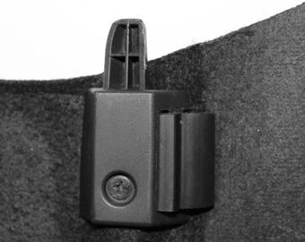 May include: A black plastic car part with a screw visible. The part is attached to a black fabric surface.