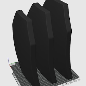 May include: Three black, curved, protective panels, likely made of ballistic material, are arranged in a row on a gray grid surface.