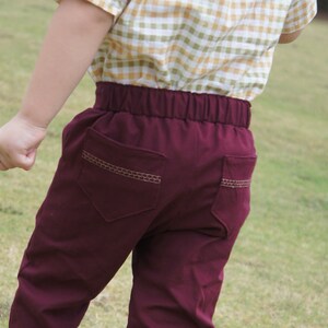 Op de afbeelding: Bordeaux broek met een bruin gestikt zakdetail. De broek heeft een elastische tailleband.