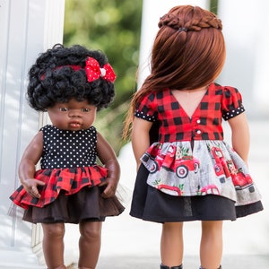 May include: Two dolls wearing red and black plaid dresses. One doll has black curly hair and a red bow. The other doll has long brown hair in a braid. Both dolls are wearing black shoes.