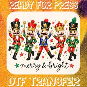 May include: A DTF transfer sheet featuring five colourful nutcracker figures in red, green, and blue uniforms with gold accents, surrounded by small stars. The text READY FOR PRESS appears at the top, and merry & bright is at the bottom.