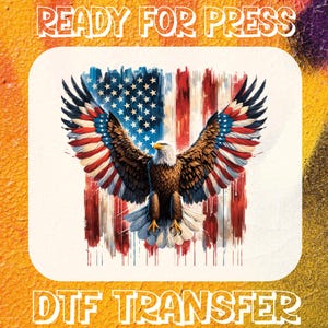 May include: A digital transfer design featuring a bald eagle with outstretched wings in front of an American flag. The eagle and flag are painted in a watercolor style with red, white, and blue colors. The design is labeled "READY FOR PRESS" and "DTG TRANSFER".