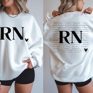 May include: White sweatshirt with the letters "RN" in black and a small black heart. The back of the sweatshirt displays "RN" and a list of positive attributes, including "compassionate" and "reliable".