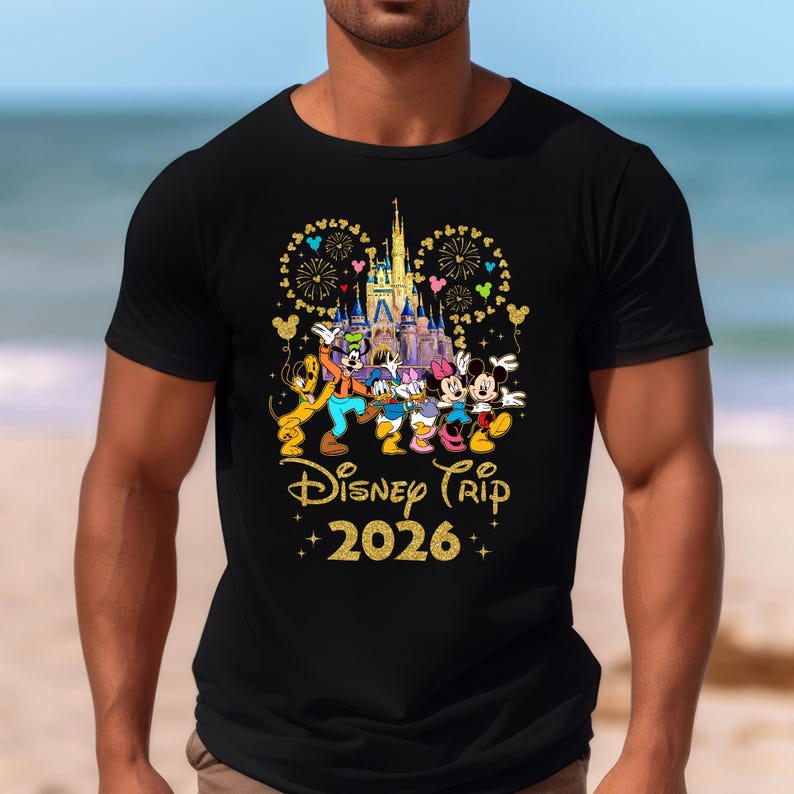 May include: Black t-shirt featuring a colorful graphic of Disney characters in front of a castle, with fireworks and balloons. The text "Disney Trip 2026" is written in gold glitter font.
