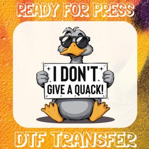 May include: A grey cartoon duck wearing sunglasses and holding a sign that says "I don't give a quack!" The sign is white with black text and a black border. The duck is sitting on a white background. The text "Ready for Press" is at the top of the image and the text "DTG Transfer" is at the bottom of the image.