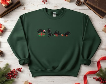 May include: A dark green sweatshirt with an embroidered design of four black cats and Christmas gifts. One cat wears a Santa hat. The design is in the centre of the sweatshirt. The sweatshirt has a crew neck and long sleeves.