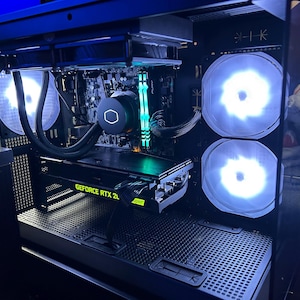 以下が含まれることがあります： 青と白の光で照らされた内部コンポーネントを備えたコンピューターケース。ケースには「GeForce RTX 20」のテキストが付いたグラフィックカード、CPUクーラー、および複数のファンが備わっています。全体的な美しさはモダンで、テクノロジーに焦点を当てています。