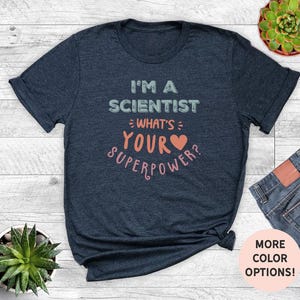 May include: A navy blue t-shirt with the text "I'm a Scientist - What's Your Superpower?" in white and pink lettering. A pink heart is included in the text.