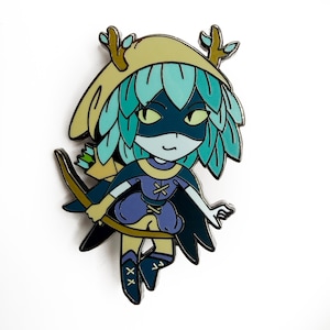 May include: A colorful enamel pin featuring a cartoon character with a teal and blue hairstyle, a mask, and a bow and arrow. The character wears a blue and purple outfit with a cape and a hat with antlers. The pin is set against a white background.
