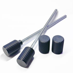 Op de afbeelding: Een assortiment zwarte en zilveren metalen voorwerpen. Twee cilindrische handgrepen met getextureerde grepen zijn bevestigd aan zilveren staven. Twee extra cilindrische objecten met getextureerde oppervlakken zijn ook aanwezig, tegen een witte achtergrond.