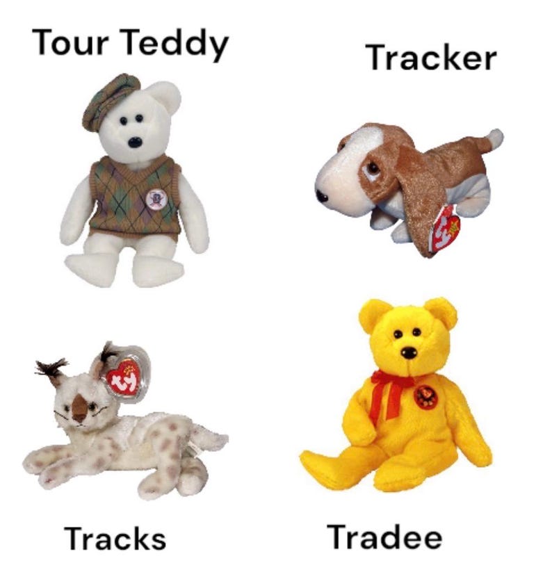 May include: Four Beanie Baby plush toys: "Tour Teddy" wearing a hat and sweater, a brown and white "Tracker" dog, a spotted "Tracks" cat, and a yellow "Tradee" bear with a red ribbon. Each has a tag.