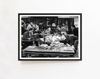 Peut inclure: Tirage encadré en noir et blanc représentant une scène de la série télévisée "Friends". L'image montre un groupe de personnes dans un café, assis sur un canapé et autour d'une table avec des magazines. L'impression est dans un cadre noir.