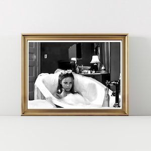 May include: Black and white framed print of a woman in a bathtub, wearing a veil and floral headpiece. The image has a vintage aesthetic, with a gold frame and a classic, cinematic feel.