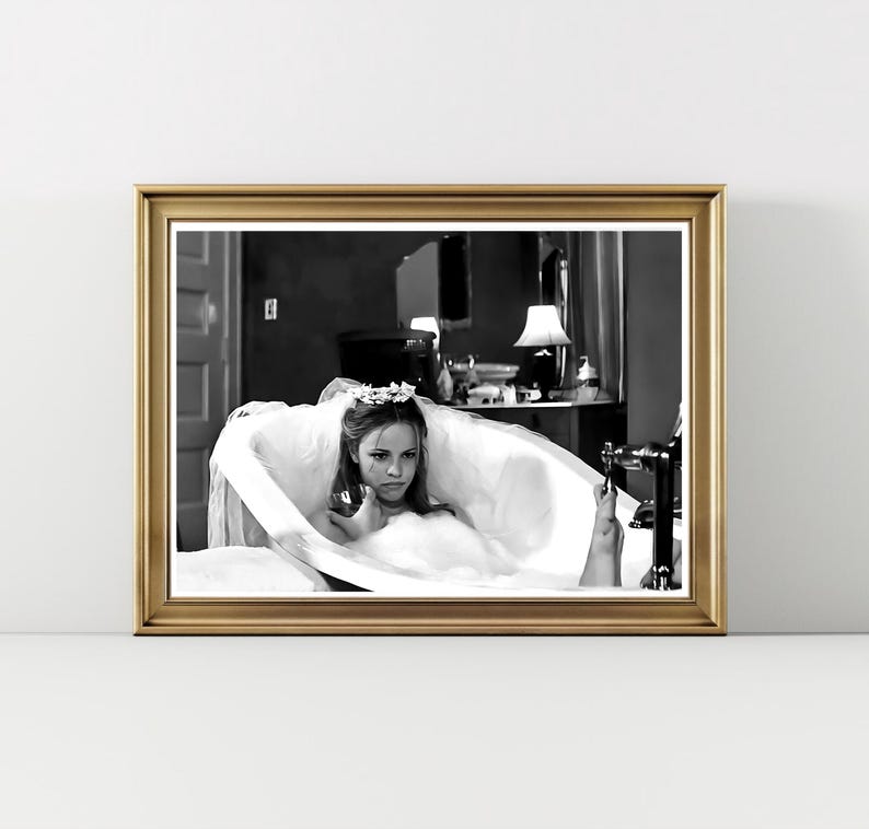May include: Black and white framed print of a woman in a bathtub, wearing a veil and floral headpiece. The image has a vintage aesthetic, with a gold frame and a classic, cinematic feel.