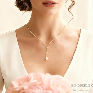 Könnte beinhalten: Eine zarte goldene Halskette mit drei Perlen, die an einer feinen Kette hängen. Die Halskette wird zu einem weißen Kleid getragen. Das Bild enthält den Text "ECHOFEELING Handcrafted Jewelry".