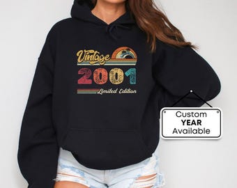 Pode incluir: Camisola de capuz preta com um design vintage 2001 em cores arco-íris. O texto "Vintage 2001 Limited Edition" está impresso na camisola.