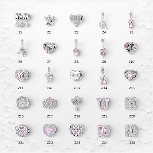 May include: A selection of silver charms with diverse designs, such as hearts, bows, angels, and bears, often embellished with pink details. Some charms display the word "MOM". These charms are suitable for bracelets or necklaces.