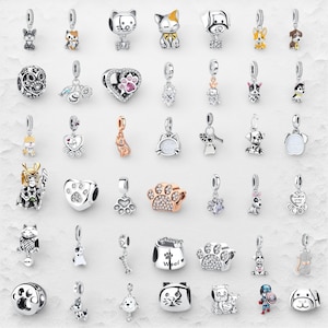 Puede incluir: Una colección de colgantes de plata con diseños de animales, incluyendo gatos, perros y huellas de patas. Algunos colgantes tienen detalles de color y están adornados con cristales. Los colgantes están diseñados para ser añadidos a una pulsera o collar.