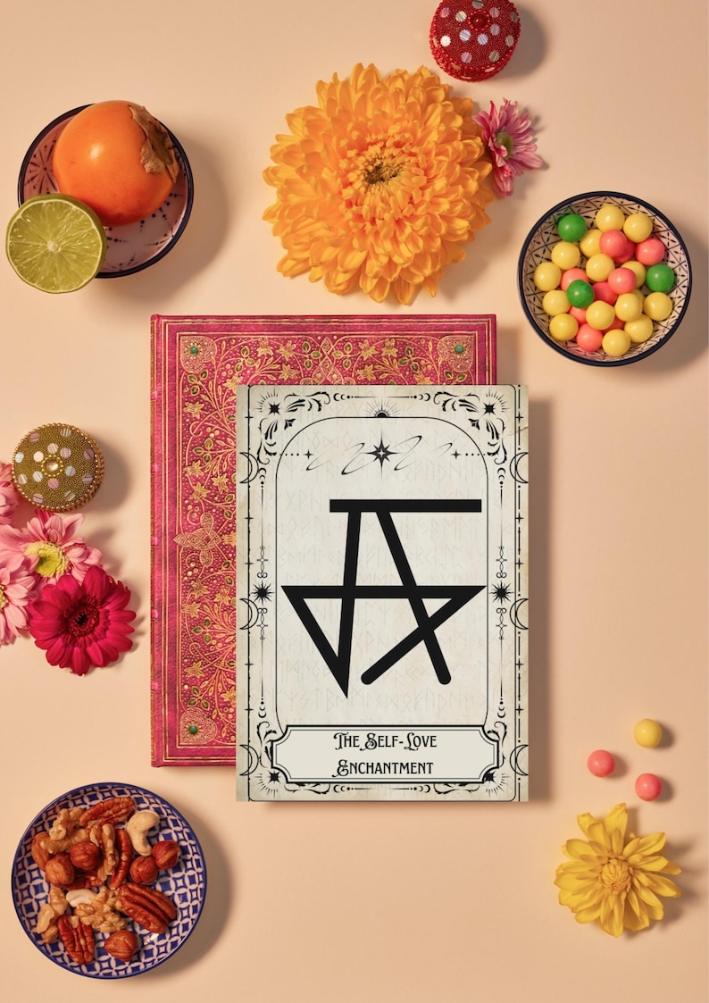 May include: A white card with a black star and the text "The Self-Love Enchantment" surrounded by a decorative border. The card is on top of a red book with a floral pattern. The image also includes a bowl of nuts, a bowl of colorful candies, a persimmon, a lime, and several flowers.