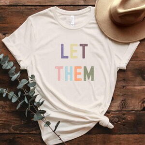 Camiseta Let Them, camiseta gráfica minimalista e colorida, camiseta com estética retrô positiva, camiseta com citação de empoderamento, camiseta com letras pastel ousadas