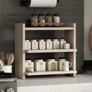 May include: A light wood two-tier spice rack featuring a top shelf with four glass jars and a bottom shelf holding several white ceramic canisters labeled with text including Salt, Tea, and Sugar, plus a white ceramic mug with a handle.