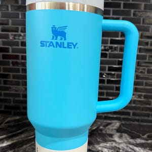 May include: A set of three ceramic mugs with a speckled, matte finish in cream, light grey, and dark grey. Each mug has a simple, minimalist design, suitable for coffee or tea.