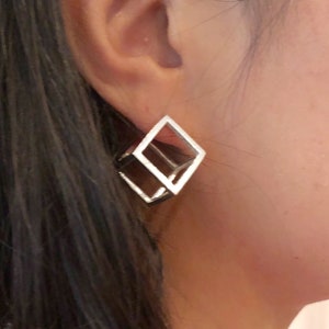 May include: Silver geometric cube earrings. The earrings are made of two interlocking squares.
