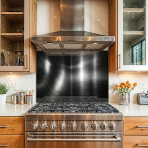Puede incluir: Una cocina de gas de acero inoxidable con seis quemadores y una campana extractora a juego. El protector contra salpicaduras presenta un diseño oscuro y texturizado. Los armarios de madera y la encimera blanca completan la cocina.
