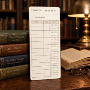 May include: A rectangular white reading log card with rounded corners featuring the text FROM THE LIBRARY OF: and YEAR STARTED: at the top. Below, a grid contains columns for TITLE, DATE, and RATING, with rows of five empty star outlines.