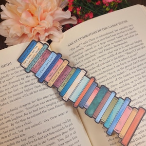 May include: A colorful bookmark featuring a stack of illustrated books with titles like "Harry Potter and the Philosopher's Stone" and "The Fellowship of the Ring." The bookmark is placed on an open book with text.