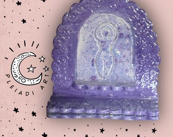 Può includere: Una mensola in ceramica viola con schienale arcuato caratterizzato da un motivo a vortice testurizzato e una figura femminile centrale in rilievo. La superficie ha una finitura maculata con toni viola chiari e scuri. Appare il testo PLEIADI ART e PLEIADIART.ETSY.COM.