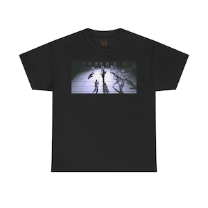 May include: Black t-shirt with a graphic print of a group of people in a white room with a checkered floor.