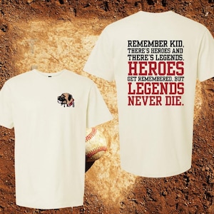 May include: Two white t-shirts, one with a cartoon dog illustration and the other with the text "Remember kid, there's heroes and there's legends. Heroes get remembered, but legends never die."