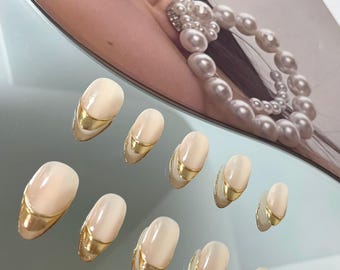 May include: Set of ten oval-shaped false nails with a light pink base and a thin gold accent band around the top edge.