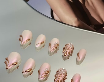May include: Set of ten pink and gold press-on nails with various designs, including swirls, lines, and abstract shapes.