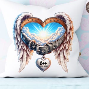 Può includere: Cuscino bianco con un design a forma di cuore con ali d'angelo e un collare per cani. Il collare incornicia una scena del cielo con nuvole e luce solare. Un'etichetta a forma di cuore recita "Boo 2015-2025". Il cuscino ha uno sfondo floreale.