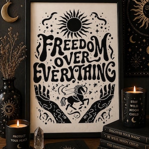 Peut inclure: Impression d'art encadrée noire avec l'inscription "FREEDOM OVER EVERYTHING". L'impression présente un soleil, des étoiles et un centaure. Des bougies, des livres et un journal sont disposés autour de l'impression, créant un thème mystique.