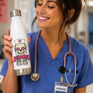 Peut inclure: Une gourde blanche en acier inoxydable avec un couvercle argenté. La gourde présente un crâne de dessin animé portant un chapeau d'infirmière et un casque, avec le texte "Cute enough to stop your heart, skilled enough to restart it."