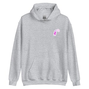 Peut inclure: Un sweat à capuche gris clair avec une poche avant et une capuche. Un petit motif rose d'un flacon pulvérisateur avec le texte "FEEL THE SPRAY" est sur le haut de la poitrine gauche. Le sweat à capuche est en matière douce.