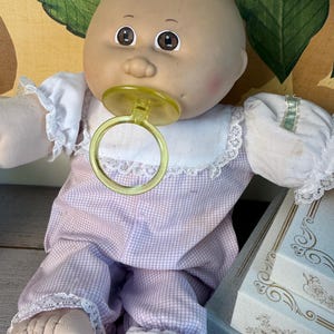 May include: A white ceramic mug with a black handle and the text "But First, Coffee" in a handwritten style. The mug is on a white surface. The mug is approximately 4 inches tall.