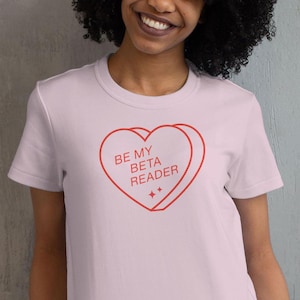 May include: Pink t-shirt with a red heart graphic that says "Be My Beta Reader".