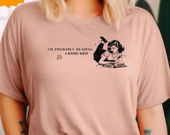 May include: A pink t-shirt with the text "I'm probably reading a reverse harem" and a black and white illustration of a woman reading a book.