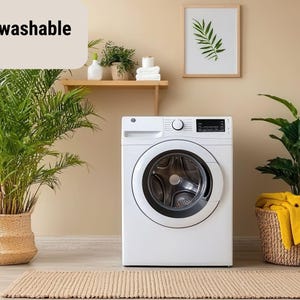 May include: A white washing machine with a black control panel is centered in a room. The text "Machine washable" is in the upper left. Potted plants and a framed botanical print decorate the space. A woven rug is on the floor.