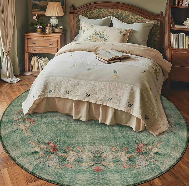 May include: A bedroom scene featuring a round, distressed green rug with floral patterns. The rug is centered beneath a bed with a floral headboard and matching bedding. The room has a vintage, cozy aesthetic.