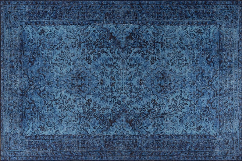 May include: A rectangular, distressed-look rug in shades of blue. The rug features a central field with a floral pattern and a darker blue border. The design has a vintage, faded appearance, suitable for home decor.