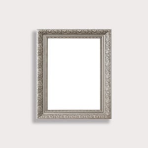May include: Silver rectangular picture frame with ornate detailing. The frame has a decorative border with scrolling patterns and a smooth, reflective surface. The frame is empty, with a white interior.