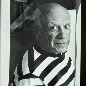 May include: Black and white photo of a man wearing a striped shirt. The text "Think different." is at the top of the photo.