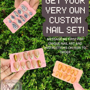 May include: Pink nail sets with various designs are displayed against a backdrop of green foliage. One set features white nails with blue floral patterns and rhinestones. Another set showcases nude nails with gold accents. The text reads: "GET YOUR VERY OWN CUSTOM NAIL SET!"