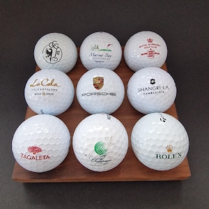 Soporte piramidal para pelotas de golf, fabricado en madera maciza de nogal, con capacidad para hasta 14 pelotas.